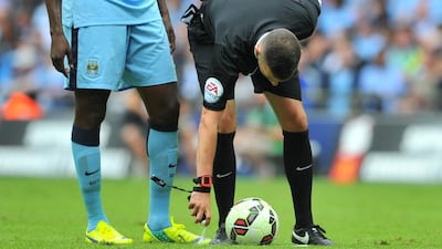 Referee Michael Oliver, right, uses the vanishing spray to mark the position of the ball for a free kick as Manchester City’s Ivorian midfielder Yaya Toure (L) watches and during the FA Community Shield football match between Arsenal Manchester City at Wembley Stadium in north London on August 10, 2014. AFP PHOTO / GLYN KIRK