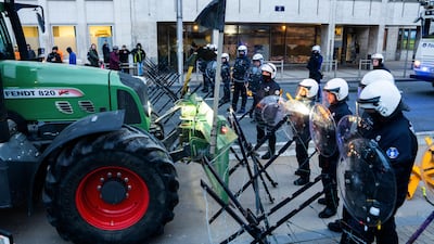 Police guard a barrier as farmers drive their tractors to block a main boulevard during a demonstration outside a gathering of European leaders at the EU Summit in Brussels. AP