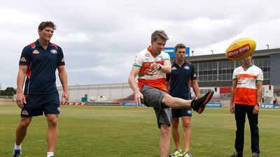 Nico Hulkenberg learns the kicking style of Australian rules football from Will Minson, left, and Shaun Higgins, right, of Western Bulldogs. Darrian Traynor / Getty Images / March 11, 2014