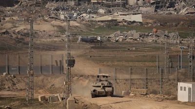 An Israeli tank moves along the border with Gaza against a backdrop of destroyed and damaged buildings. Getty Images
