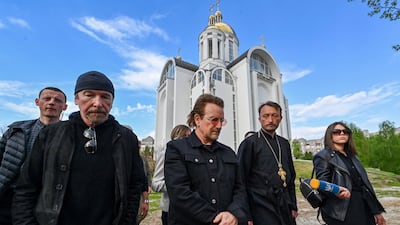 The priest guides the musicians to the site of the mass grave in Bucha. AFP