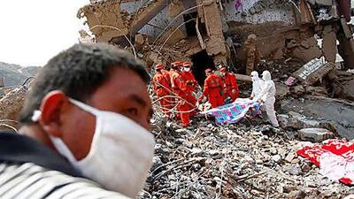Rescuers remove a body from the debris in the landslide-hit Zhouqu county today.