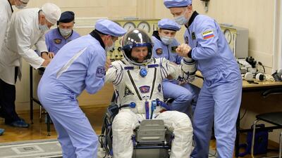 Russian Space Agency experts help Nick Hague to stand up after inspecting his space suit. AP Photo