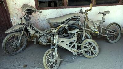epa04057341 A motorbike and bicycles covered with volcanic ash from the Mount Sinabung eruption are left in front of a house at Sibintun village in Karo, North Sumatra, Indonesia, 06 February 2014. A man who was injured in last week’s volcanic eruption on the Indonesian island of Sumatra island died on 05 January, bringing the death toll from the disaster to at least 16, a disaster management official said. Dedi Sahputra / EPA