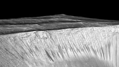 A handout image released by Nasa on September 28, 2015 showing dark narrow streaks called recurring slope lineae (RSL) emanating out of the walls of Garni crater on Mars. EPA/NASA handout