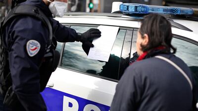 A police officer issues a fine to a woman who is outdoors without permission, at the entrance of the open-air market of Belleville, in Paris on March 20, 2020. AP Photo