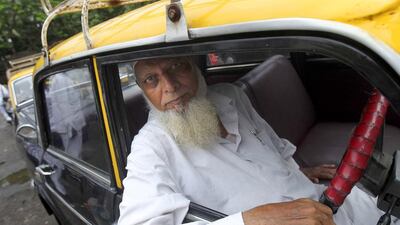 An Indian taxi driver poses for photos from inside his vehicle in Mumbai, India. More than 4,500 Premier Padmini taxis are expected to be banned from the roads in Mumbai this year in line with a government order that bans cabs that are more than 20 years old. Rafiq Maqbool / AP Photo