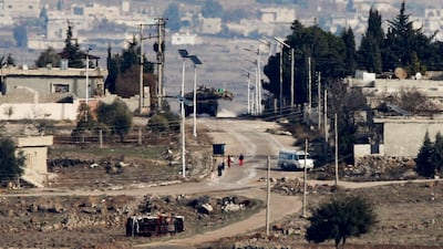 People walk near a military vehicle at Quneitra crossing which connects the Israeli-occupied Golan Heights and Syria, as seen from the Israeli-occupied Golan Heights, December 10, 2024. REUTERS