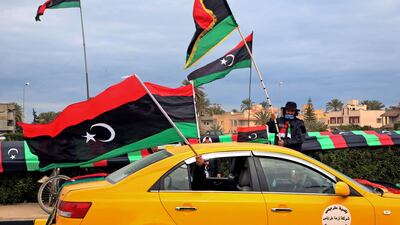 People wave flags from a taxi in Tripoli as part of the celebrations. AFP