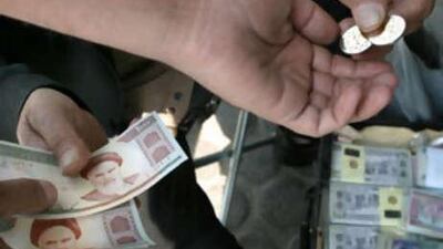 An Iranian man exchanges new 800 rial coins, introduced to reduce the cost of printing paper money, from a currency trader in Tehran.