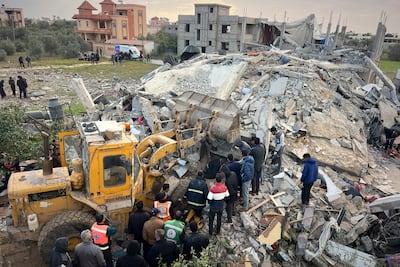 Volunteers and rescue workers use a bulldozer to remove the rubble of a building hit by an Israeli air strike in Khan Younis. AP
