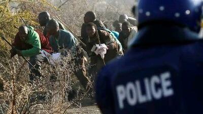 A policeman fires at protesting miners outside a South African mine in Rustenburg, 100 kilometres north-west of Johannesburg. Nearly three dozen miners were killed in the bloodiest incident of state violence since the days of apartheid. Siphiwe Sibeko / Reuters