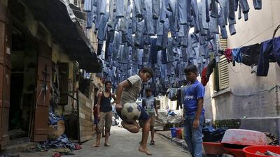 Mohammad Afroze, 15, plays soccer in an alley as used pairs of jeans are hung to dry before they are sold in a second-hand clothes market. Afroze said he loves Kolkata because he was born in the city and people love to play soccer.