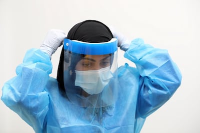 Rouda Al Hameli, an Emirati nurse at the field hospital in Sharjah, puts on her PPE for a ward round. Chris Whiteoak / The National