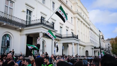 Supporters wave the Syrian flag outside the reopened embassy in London. Sana
