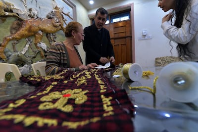 Iraqi priest Ammar Yaqo looks on as Karjiya Baqtar embroiders a precious prayer shawl using golden thread, to gift to Pope Francis during his visit to her Iraqi hometown Qaraqosh, in the Nineveh province. AFP