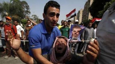 Members of the Muslim Brotherhood and supporters of deposed Egyptian president Mohammed Morsi grieve in front of soldiers outside the Republican Guard headquarters in Cairo.