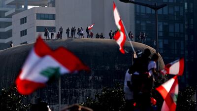 Lebanese wave the national flag atop “The Egg” during demonstration to demand better living conditions. AFP