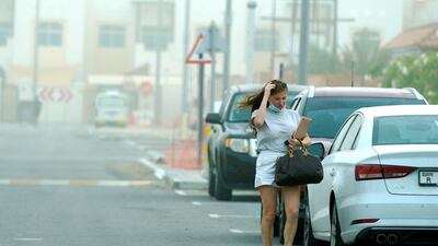 A woman gets out of her car amid dusty weather at Khalifa City in Abu Dhabi. The National