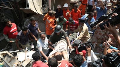 Pakistani volunteers carry an injured person rescued from a collapsed residential building in Karachi on July 18, 2017. Shakil Adil / AP