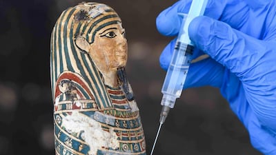 An archaeologist cleans a statue during the unveiling of an ancient treasure trove of more than a 100 intact sarcophagi. AFP