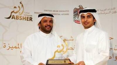Khalifa Al Mari, right, of the Ministry of Health accepts an Absher Award from the Ministry of Labour’s Humaid bin Deemas during a ceremony in Abu Dhabi yesterday. Christopher Pike / The National
