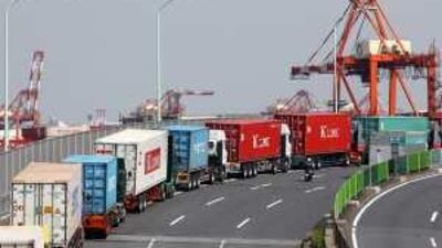 Lorries transport containers near a shipping terminal in Tokyo. Japan's economy grew less than estimated in the second quarter.