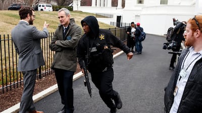 A Secret Service officer rushes past reporters after a vehicle rammed into a security barrier near the White House.