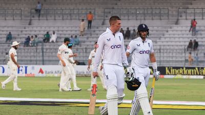 England's Zak Crawley and Joe Root walk off the field at stumps in the deserted stadium at Multan. Reuters
