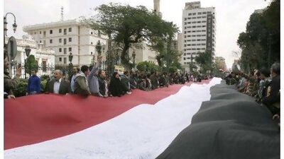 Protesters waved a giant flag near the Egyptian parliament in Cairo yesterday, while business and government leaders expressed concern about the impact of disruptions on the country's economy.