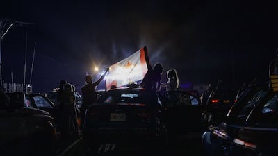 Concert-goers hold up a Canadian Flag during a singing of the Canadian national anthem during a drive-in Dean Brody concert to celebrate Canada Day in Markham, Canada. While most events marking the 153rd anniversary of Confederation across the country have been cancelled or moved online due to the spread of the coronavirus, the drive-in concert skirted social gathering rules by allowing attendees to socially distance in and on their cars. AFP