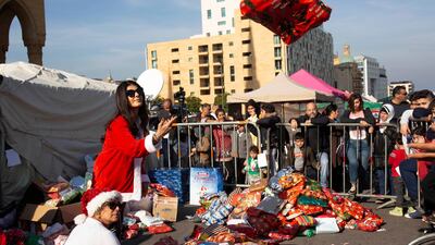 Volunteer Ibtisam Nablussi tosses a Christmas present, as anti-government protesters distribute clothing to the needy ahead of Christmas, at Martyrs Square in Beirut, Lebanon. AP Photo