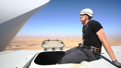 An engineer works at the top of a turbine.
