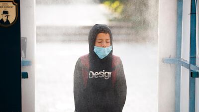 An elementary school pupil wearing face mask passes through a disinfection tunnel on the first day of school in Pristina, Kosovo. EPA