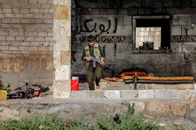One of Turkish-backed Syrian rebel fighters walks with a Kalashnikov assault rifle at a position along the battle frontlines with the Syrian Democratic Forces (SDF) in the countryside of Syria's northern city of Manbij, on June 8, 2022. AFP