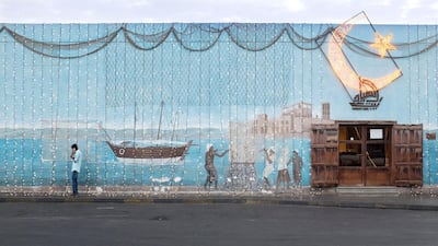 A man walks by a fish market's building that's adorned with lights in celebration of Ramadan. June 23, 2015. Reem Mohammed / The National