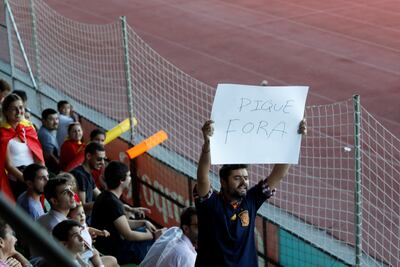 A man displays a banner that reads 'Pique Out', referring to Gerard Pique, before a training session this week. Rafael Marchante / Reuters