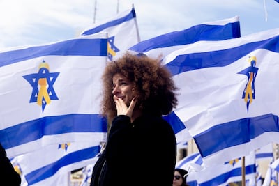 A woman grieving among Israeli flags in "Hostages Square" in Tel Aviv prior to the handover on February 20 of four bodies of hostages taken by Hamas during its deadly October 2023 on Israel. Getty Images.