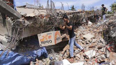 A man removes a box of food from under the rubble of a building that collapsed after the earthquake in Pidie Jaya. Heri Juanda / AP Photo