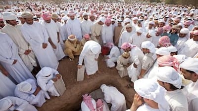 Friends and family gather around the grave as the body of Salem Saif al Mazroui is covered in a cemetery near Saif Bin Ali Al Khatra Mosque in Adhen, Ras al Khaimah.