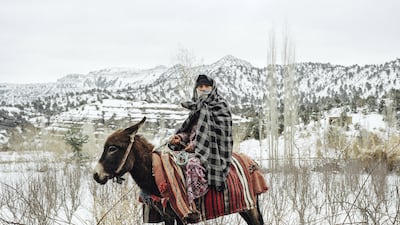 An Amazigh woman transports water and apples back to her village a day after a blizzard hit the High Atlas Mountains in Morocco. Courtesy Yumna Al-Araishi