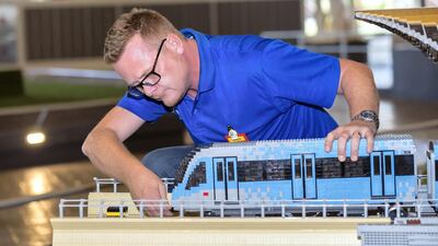 Lego builder James Bailey inspects the lego structures in Miniland. Chris Whiteoak / The National