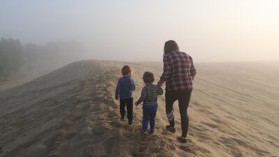 A family goes for an early morning walk in the desert during heavy fog in Dubai. Chris Whiteoak / The National