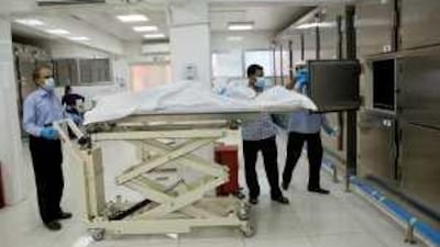 Workers at the mortuary section of Sheikh Khalifa Medical City put a body into a refrigerator.