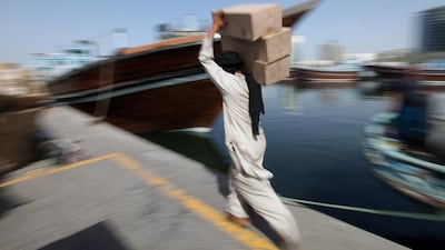 A worker carries goods to transport to traditional dhows at Al-Khor in the Dubai Creek area. Ali Haider / EPA