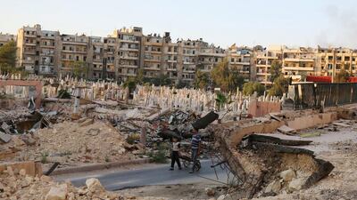 People walk near an over-crowded graveyard in the rebel-held Al Shaar neighbourhood of Aleppo on October 6, 2016. Abdalrhman Ismail/Reuters