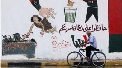 A man cycles past graffiti depicting Muammar Qaddafi with Arabic writing reading, "Keep your city clean, Libya is free, Historical garbage" in Tripoli on Wednesday. Abdel Magid al Fergany / AP Photo