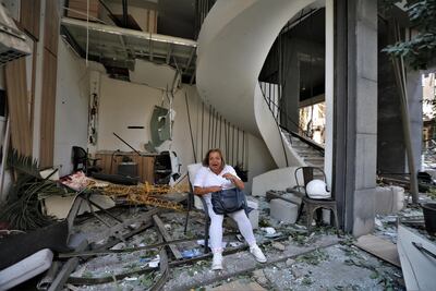 A woman sits in front of a damaged building in Beirut. EPA