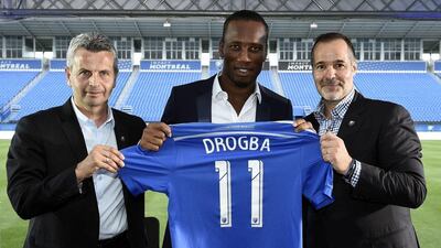 Didier Drogba, centre, poses with a Montreal Impact shirt next to club president Joey Saputo, right, and coach Franck Klopas. Franck Fife / AFP