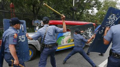 Police officers wave riot shields and batons at protesters fleeing the scene in jeepneys.